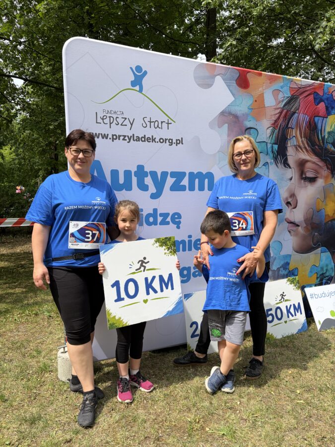 Biegacze na ściance z napisem "Autyzm widzę, rozumiem, pomagam".